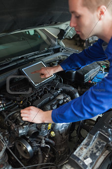 Mechanic with tablet pc repairing car
