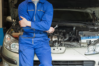 Mechanic leaning on car with open hood