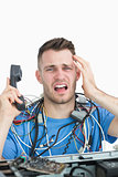 Portrait of frustrated computer engineer on call in front of open cpu
