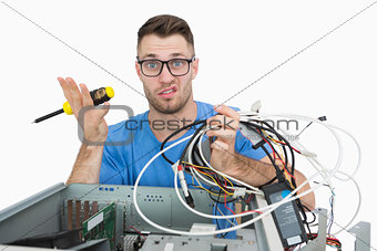 Portrait of confused it professional with screw driver and cables in front of open cpu