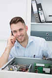 Portrait of smiling computer engineer on call in front of open cpu