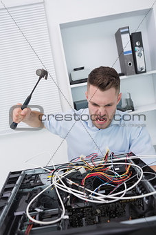 Frustrated man hitting cpu with hammer