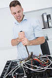 Frustrated man using hammer to pull out wires from cpu