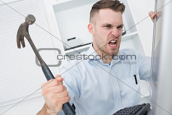 Frustrated man hitting computer monitor with hammer