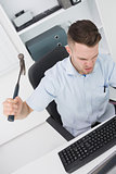 Frustrated man hitting computer monitor keyboard with hammer