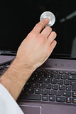 Hand examining laptop screen with stethoscope