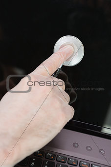 Hand examining laptop screen with stethoscope