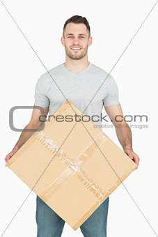Portrait of young man carrying cardboard box
