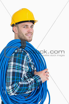 Portrait of smiling young male architect carrying coiled blue tubing