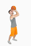 Side view of a young man throwing basketball
