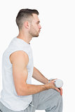 Side view of young man exercising with dumbbell