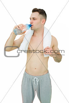 Shirtless man drinking water with towel around neck