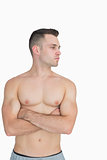 Bare chested man with arms crossed looking to his side