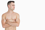 Bare chested man with arms crossed looking to his side