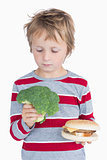Young boy holding broccoli and burger