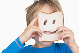 Young boy looking through holes in bread slice