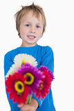 Portrait of cute young boy holding out flowers