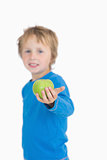 Portrait of young boy holding out a green apple