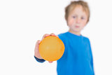Young boy holding out an orange