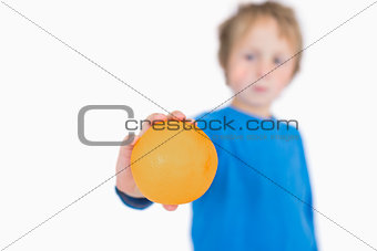 Young boy holding out an orange