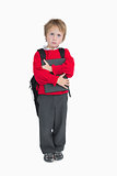Young boy with schoolbag and book standing