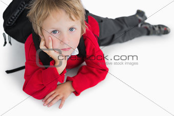 Boy lying on floor with schoolbag