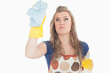 Beautiful young maid using duster and disinfectant spray