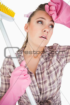 Tired young woman holding broom