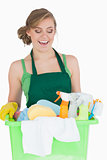Happy young maid carrying cleaning supplies