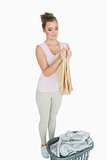 Young woman folding towel with laundry basket