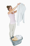 Woman examining shirt with laundry basket