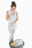 Young woman folding shirt with laundry basket