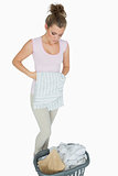 Young woman folding shirt with laundry basket