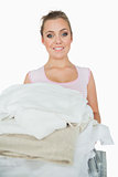 Portrait of smiling woman carrying stack of clothes