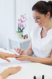 Manicurist using nail brush on womans nails