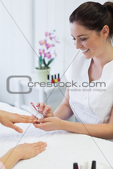 Manicurist using nail brush on womans nails