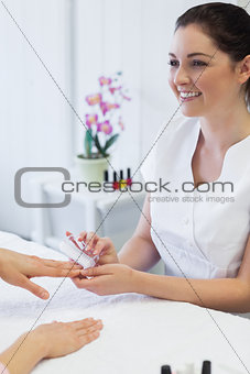 manicurist using nail brush on womans nails