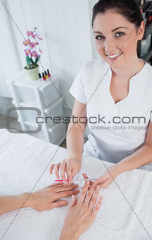 Portrait of manicurist filing womans nails