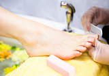 Closeup of nail technician filing womans toe nails