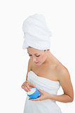 Young woman wrapped in towel applying cream