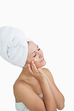 Woman wrapped in towel applying cream on face