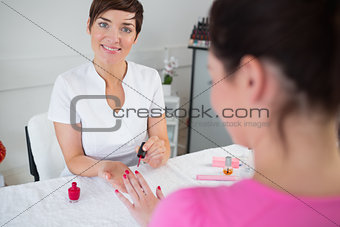 Young woman applying nail varnish to finger nails