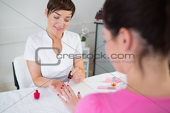 Nail technician applying nail varnish to finger nails