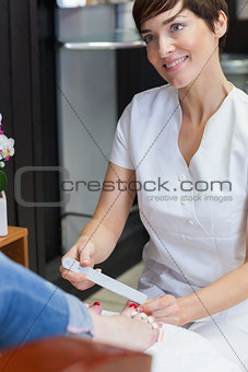 Nail technician filing womans toe nails