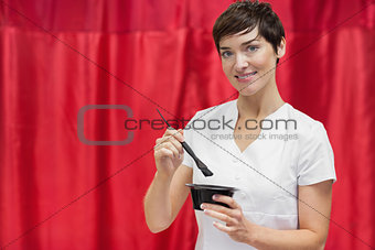 Young woman mixing hair color over red backdrop
