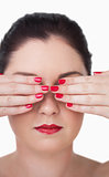 Sensuous young woman covering eyes with red painted finger nails