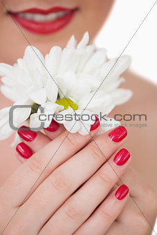 Closeup of woman with red lips and red painted nails holding flowers