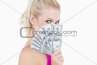 Woman holding fanned banknotes in front of face