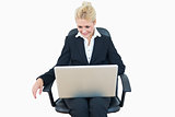 Happy business woman using laptop on chair