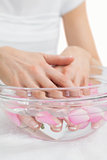 Womans hands in bowl with petals at hands spa